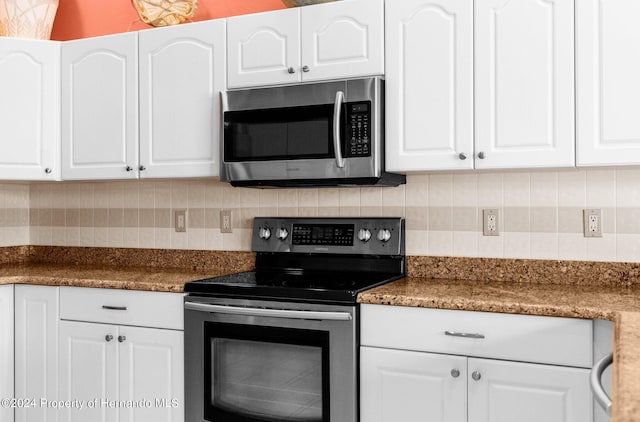 kitchen featuring white cabinets, stainless steel appliances, dark stone counters, and backsplash