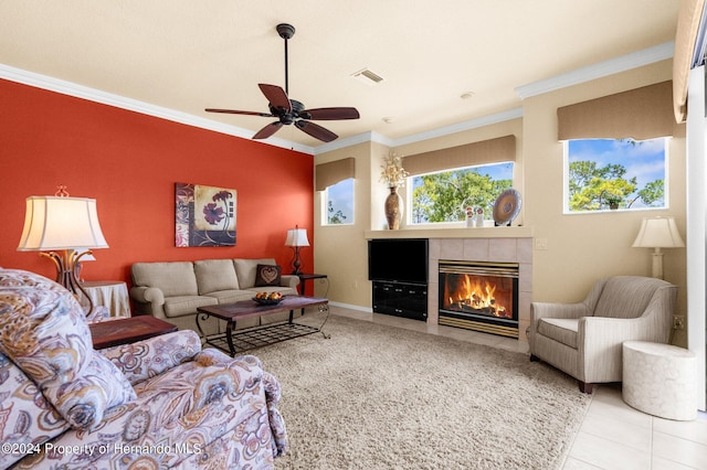 tiled living room with a tiled fireplace, ceiling fan, and crown molding