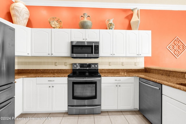 kitchen with appliances with stainless steel finishes, tasteful backsplash, dark stone counters, crown molding, and white cabinets