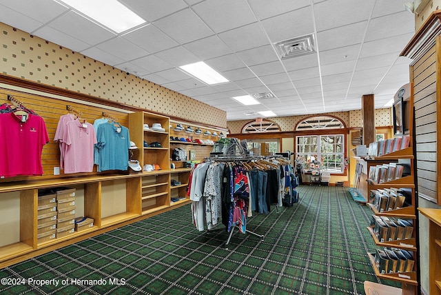 walk in closet with a drop ceiling and dark colored carpet