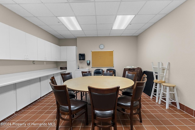 dining area with dark tile patterned flooring and a drop ceiling