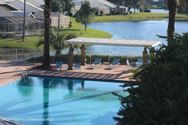 view of swimming pool with a lawn, a patio, and a water view