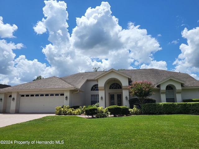 ranch-style house with a garage, french doors, and a front yard