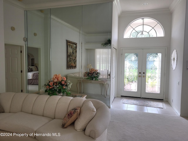 tiled foyer with a towering ceiling, french doors, and crown molding