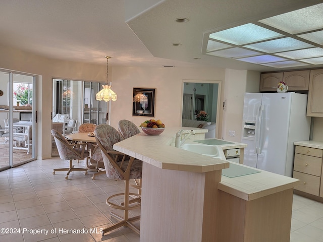 9355 Southern Belle Dr, Weeki Wachee, FL 34613 - kitchen with tile counters, white refrigerator with ice dispenser, a sink, light tile patterned floors, and a breakfast bar area
