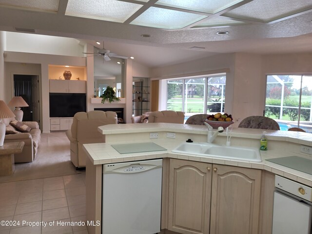 kitchen with light tile patterned floors, white dishwasher, ceiling fan, tile countertops, and sink