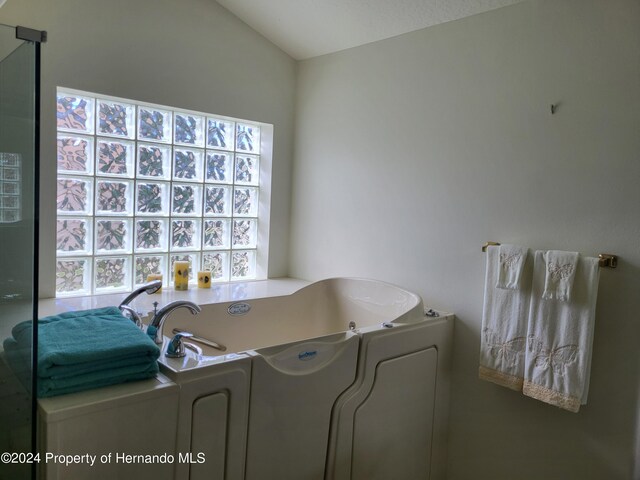 bathroom featuring lofted ceiling and a bathing tub