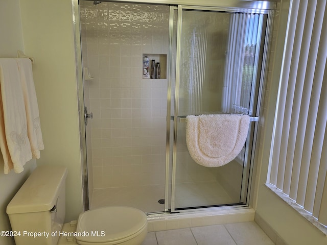 bathroom featuring toilet, tile patterned flooring, and a shower with door