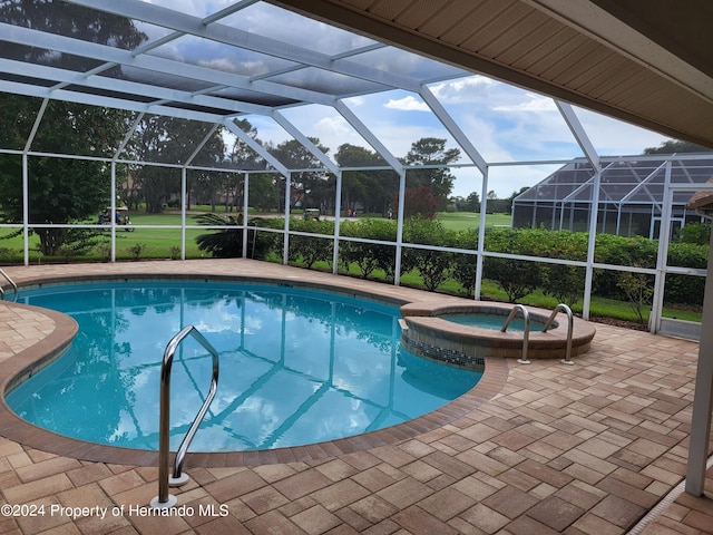 view of swimming pool with a patio, glass enclosure, and an in ground hot tub