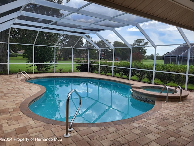 view of swimming pool featuring a yard, a lanai, an in ground hot tub, and a patio