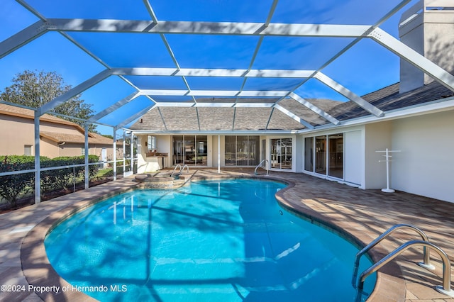 view of swimming pool featuring a lanai, an in ground hot tub, and a patio area