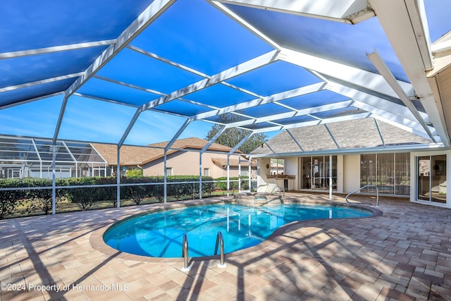 view of swimming pool featuring a patio, glass enclosure, and an in ground hot tub