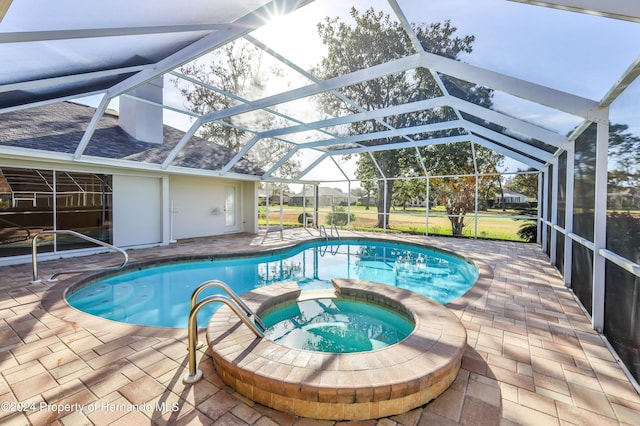 view of pool featuring a patio area, glass enclosure, and an in ground hot tub