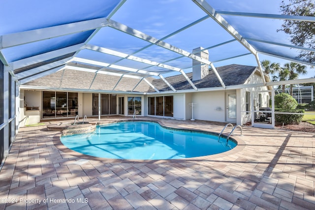 view of swimming pool featuring a jacuzzi, glass enclosure, and a patio