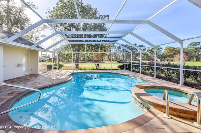 view of pool featuring a patio, glass enclosure, and an in ground hot tub