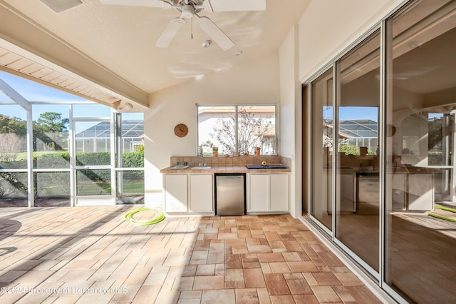 unfurnished sunroom featuring ceiling fan and sink