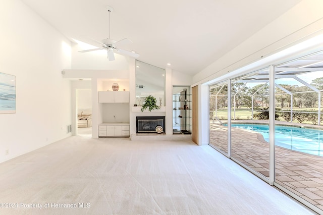 unfurnished living room with high vaulted ceiling, light colored carpet, and ceiling fan