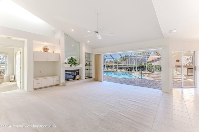 unfurnished living room with high vaulted ceiling, light carpet, ceiling fan, and built in features