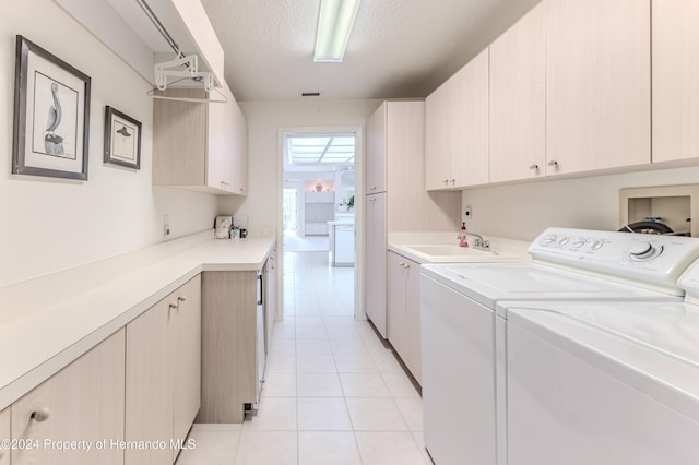 laundry area with independent washer and dryer, a textured ceiling, light tile patterned floors, cabinets, and sink