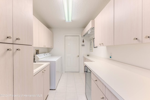 laundry room with washer and dryer, cabinets, a textured ceiling, and light tile patterned floors