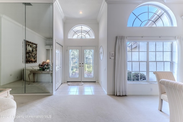 carpeted entrance foyer with a high ceiling, french doors, and crown molding