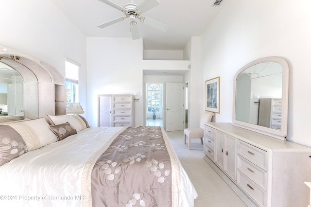 carpeted bedroom featuring ceiling fan and a high ceiling