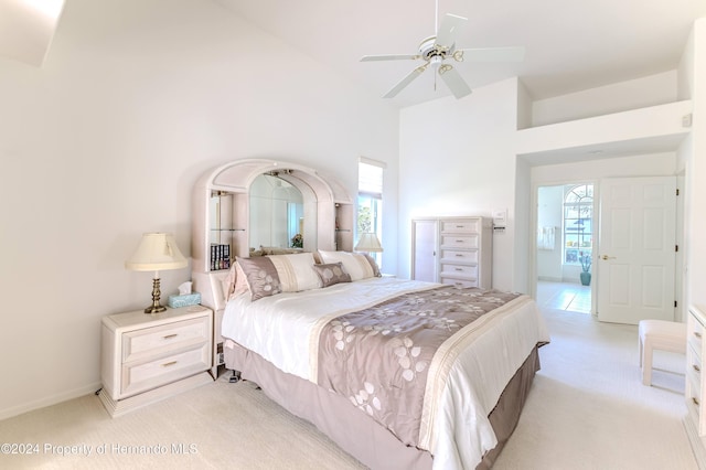 bedroom featuring high vaulted ceiling, ensuite bath, light carpet, and ceiling fan