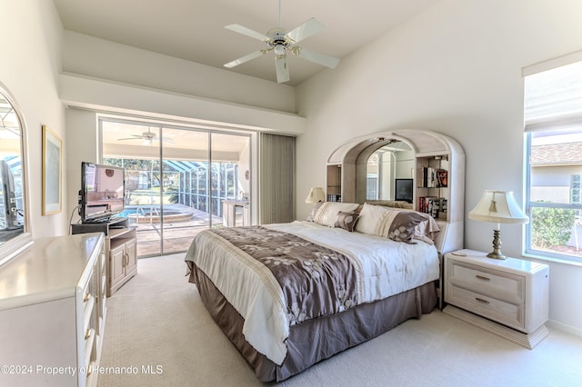 carpeted bedroom with access to outside, ceiling fan, and a high ceiling