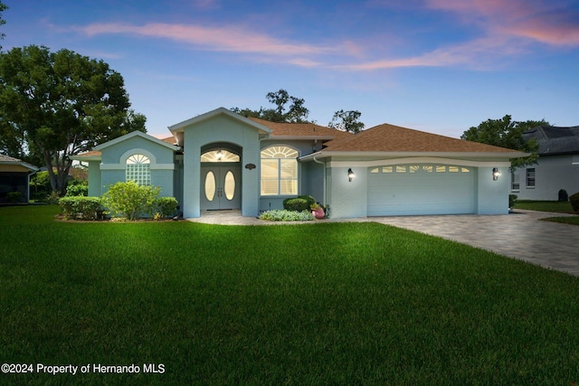 view of front of property with a garage and a yard