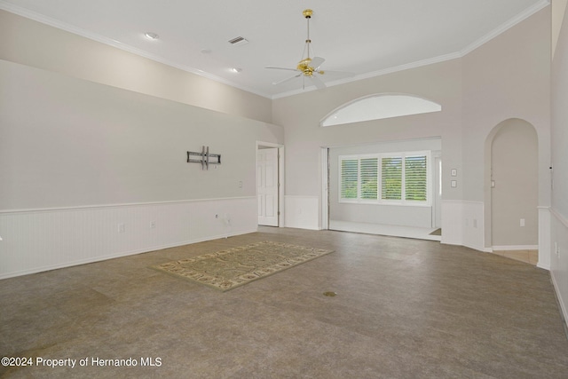 empty room featuring a high ceiling, ceiling fan, and crown molding