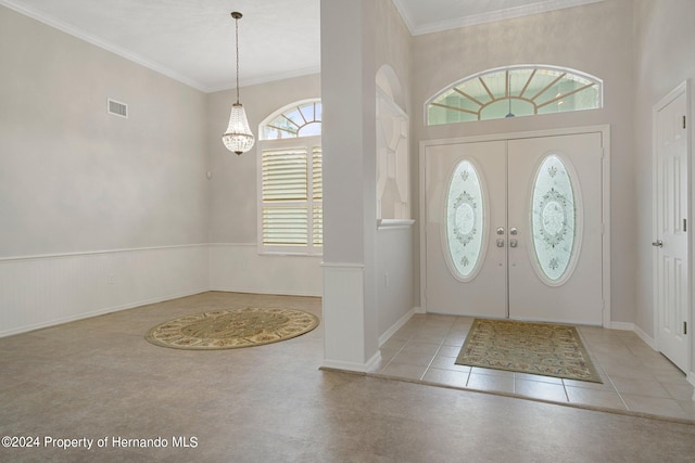 tiled entrance foyer featuring a wealth of natural light, a chandelier, crown molding, and french doors