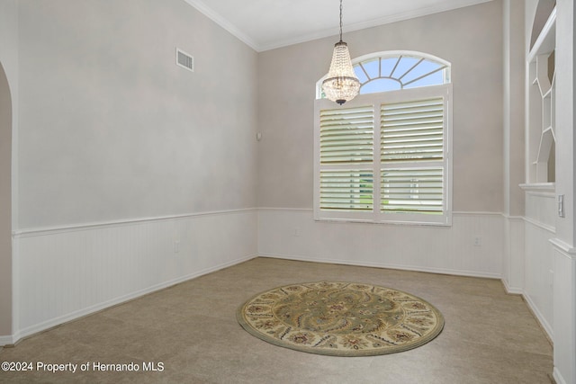 spare room featuring ornamental molding, plenty of natural light, and an inviting chandelier