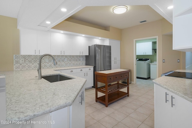 kitchen featuring stainless steel refrigerator, white cabinetry, sink, and backsplash