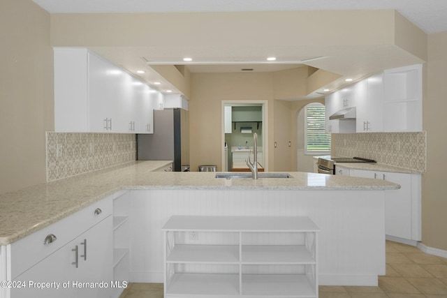 kitchen featuring tasteful backsplash, stainless steel appliances, light stone countertops, white cabinets, and kitchen peninsula