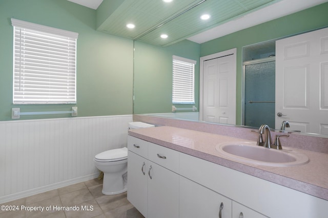 bathroom featuring toilet, vanity, tile patterned floors, and a shower with door