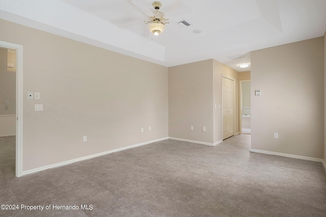 unfurnished room featuring light colored carpet, ceiling fan, and a raised ceiling