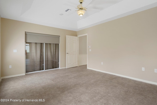 unfurnished bedroom with a tray ceiling, a closet, carpet, and ceiling fan