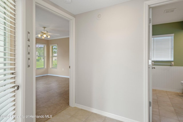 corridor featuring light colored carpet and crown molding