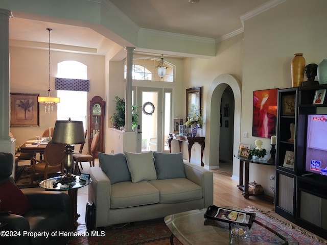 living room with light hardwood / wood-style floors, ornamental molding, and decorative columns