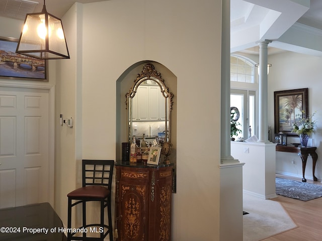 hall with decorative columns, light hardwood / wood-style floors, and crown molding