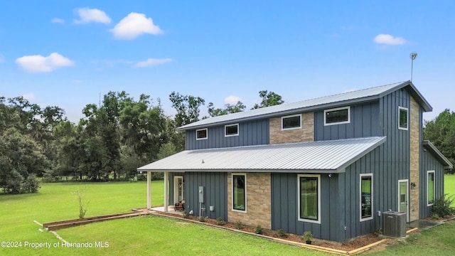 rear view of house featuring cooling unit and a yard