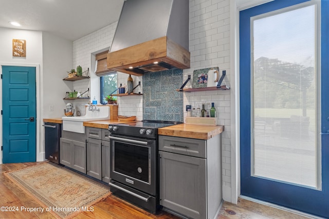 kitchen with gray cabinetry, wooden counters, electric stove, light wood-type flooring, and custom exhaust hood