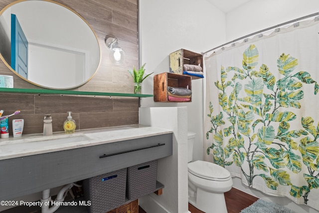 bathroom featuring toilet, tasteful backsplash, sink, and walk in shower