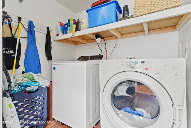 clothes washing area with hardwood / wood-style floors and washer and clothes dryer