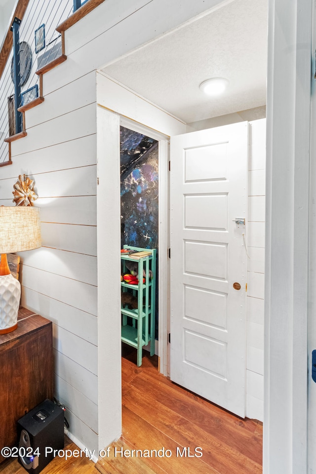 corridor featuring hardwood / wood-style floors, wood walls, and a textured ceiling