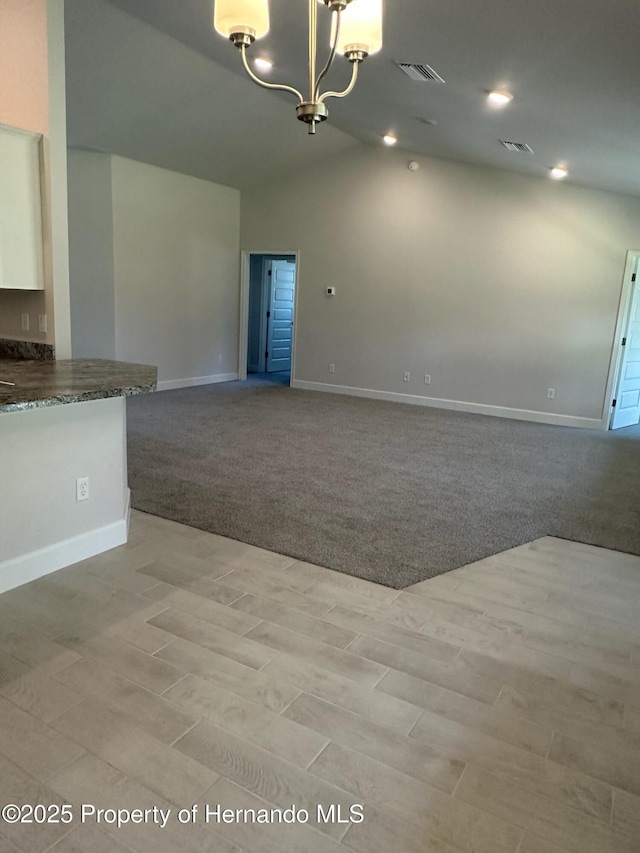 interior space with vaulted ceiling, a notable chandelier, light colored carpet, and visible vents