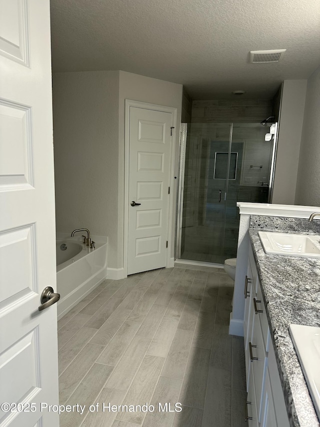 full bathroom featuring a garden tub, a sink, a shower stall, double vanity, and wood tiled floor