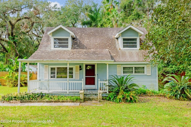 cape cod home featuring a front yard and a porch