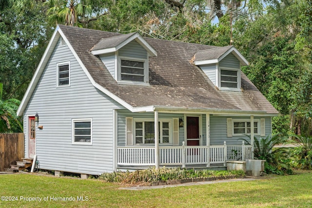 new england style home featuring a front yard and covered porch