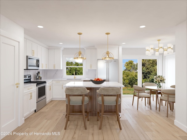 kitchen with stainless steel appliances, decorative light fixtures, light hardwood / wood-style flooring, a center island, and white cabinets